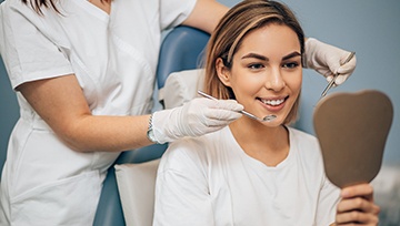 A young female looking at her smile in the mirror after a dental checkup and cleaning