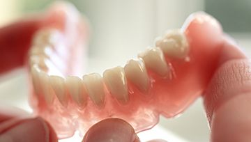 Hand holding full denture
