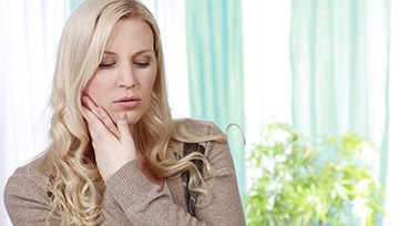 Woman who needs an emergency dentist in Ann Arbor holding her mouth