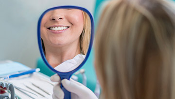 Woman looking at teeth in mirror