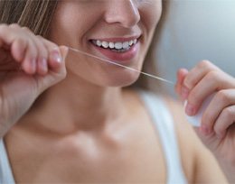 Woman flossing her dental implants in Ann Arbor