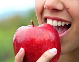 Closeup of patient with dental implants in Ann Arbor eating an apple