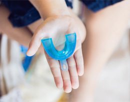 Hand holding mouthguard to protect dental implants in Ann Arbor 