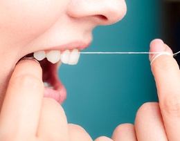 Woman flossing to prevent dental emergency in Ann Arbor