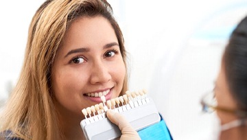 dentist holding veneers up to a patient’s smile
