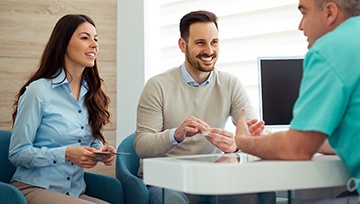 Dentist and couple talking in dental office