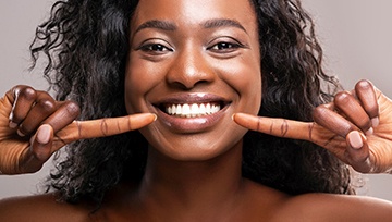 Woman with white teeth pointing to smile