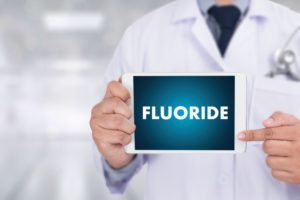 a doctor holding a sign that reads “Fluoride”