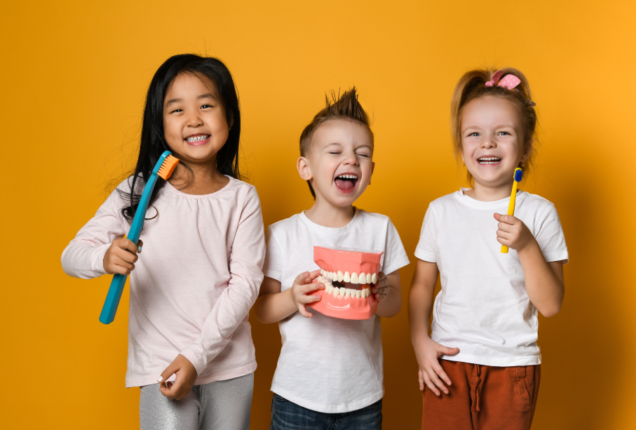 Kids holding giant toothbrushes and dentures